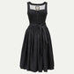 Black dirndl dress with a textured bodice, decorative front buttons, and a full gathered skirt tied with a matching waist bow