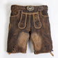 Brown suede lederhosen with dark floral embroidery, contrast piping and antique deer buckle belt