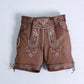 Brown Bavarian-style lederhosen shorts for women featuring ornate embroidery, front bib, and lace-up leg hems
