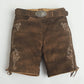Rustic brown women lederhosen with light floral embroidery, side lace ties, and a decorative deer buckle belt